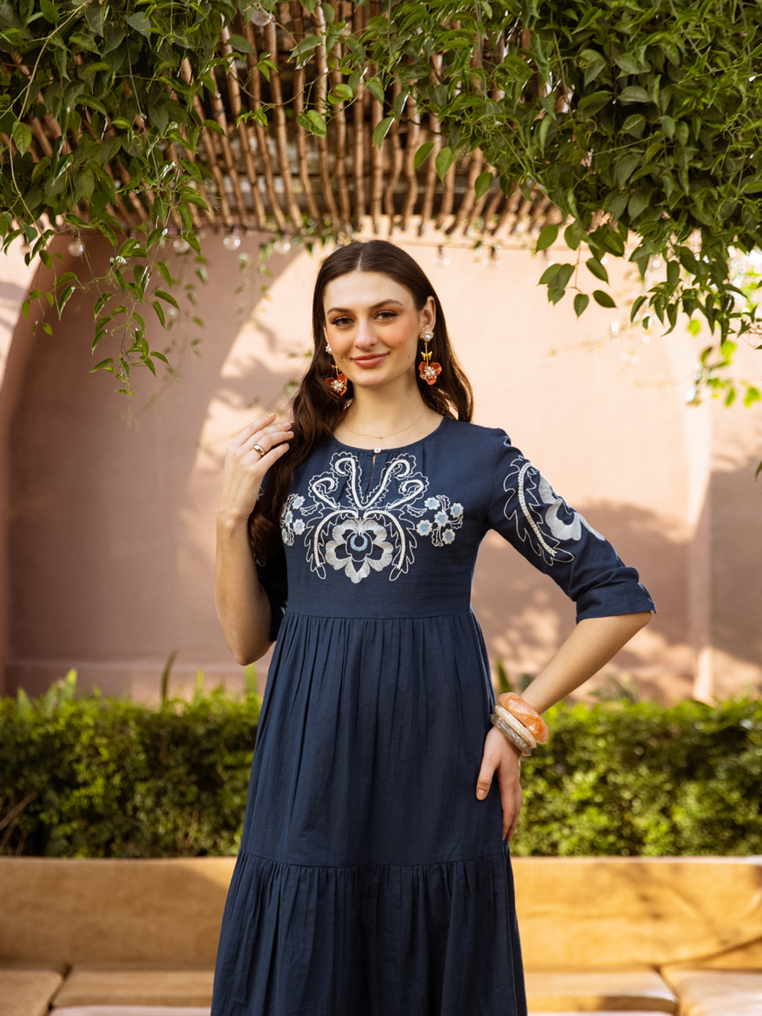 Woman wearing a navy blue dress with white embroidery outdoors